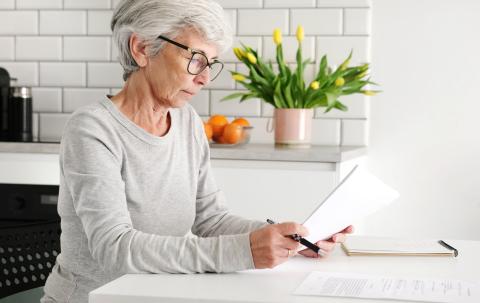 Mujer mayor ordenando documentos en casa 