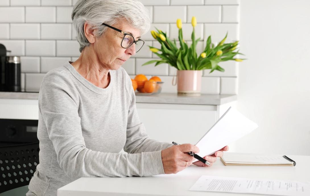 Mujer mayor ordenando documentos en casa 