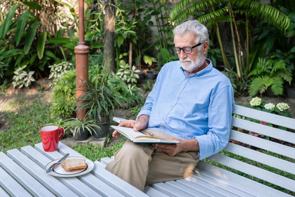 Señor mayor leyendo en un jardín